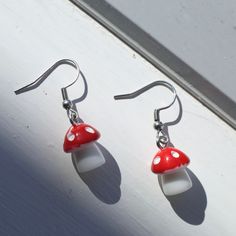 Add some cute flair to your wardrobe with these stylish dangle earrings! Handcrafted from high-quality steel, and plastic materials, these unique earrings are the perfect whimsical everyday pair! With their eye-catching design and bright red colour, these earrings are perfect for adding a fun and trendy twist to any outfit.  Make a statement and show off your love for funky jewellery with these one-of-a-kind earrings that are sure to turn heads wherever you go! Hooks are made from surgical steel, and are suitable for most sensitive ears. Lengths of earrings may vary within pairs. Domestic/Australian Standard shipping is not tracked. If you would like tracking with your order, please select the 'tracked' option at checkout.  :) Fun Mushroom Design Jewelry For Gifts, Fun Mushroom Design Jewelry Gift, Quirky Hypoallergenic Dangle Earrings, Playful Plastic Dangle Jewelry, Cute Adjustable Resin Earrings, White Mushroom Design Drop Earrings, Whimsical White Mushroom Design Earrings, Cute Dangle Earrings With Mushroom Design, Cute Mushroom Design Dangle Earrings