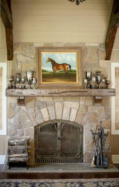 a fireplace with a horse painting on the mantle and vases sitting next to it