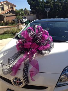 a white car with a pink and black bow on it