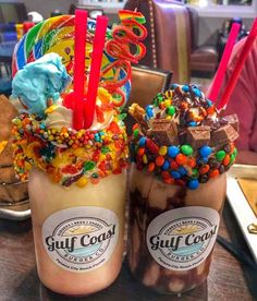 two glasses filled with ice cream and toppings on top of a table next to each other