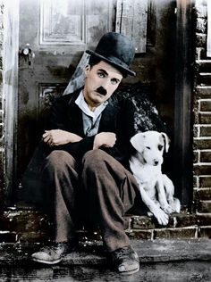 a man sitting on the steps with a dog in front of him and wearing a top hat