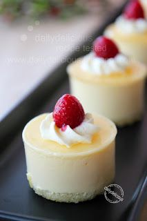 three small desserts with whipped cream and raspberries are on a black tray