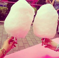 two cotton candy lollipops are being held up by someone's hands