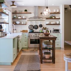 a kitchen with wooden floors and lots of open shelving on the wall above the stove