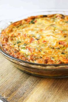 a casserole dish with cheese and vegetables in it sitting on a wooden cutting board