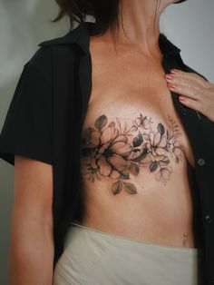 a woman's chest with flowers on it and a black jacket over her shoulder