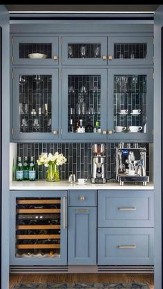 a kitchen with blue cabinets and wine glasses on the glass shelves in front of it