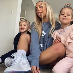 a woman and two children sitting on the floor with their tongue hanging out in front of them