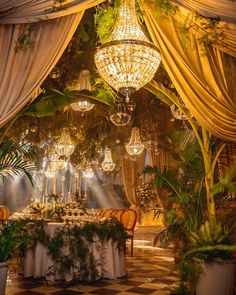 an indoor dining area with chandeliers and tables set for dinner, surrounded by greenery