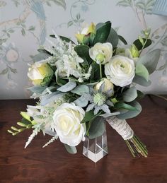 a vase filled with white flowers on top of a wooden table