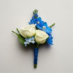 a blue and white boutonniere with flowers on the top is laying against a wall