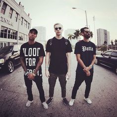 three young men standing in the middle of a street