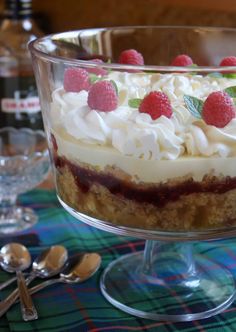 there is a dessert in the glass bowl with raspberries and whipped cream on top