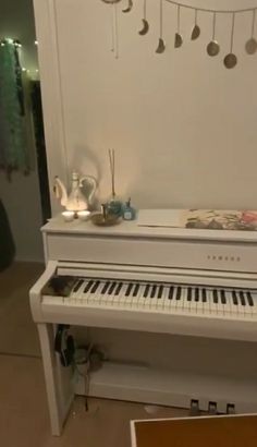 a white piano sitting in front of a wall with ornaments hanging from it's sides