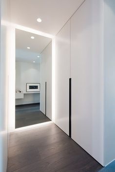 an empty room with white walls and wood flooring is lit by recessed lighting