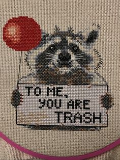 a raccoon holding a sign that says to me you are trash