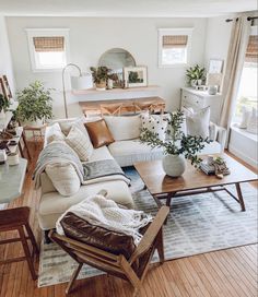 a living room filled with lots of furniture and plants on top of a hard wood floor