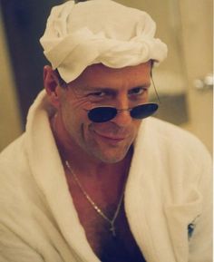 a man in a bathrobe is smiling and wearing eye patches on his face