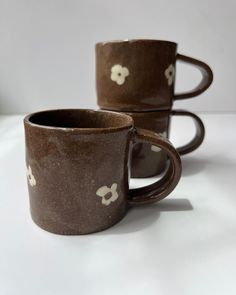 three brown coffee mugs with white flowers on them