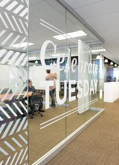 an office with glass walls and people sitting at desks