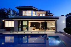 a house with a swimming pool in front of it at night, as seen from the outside