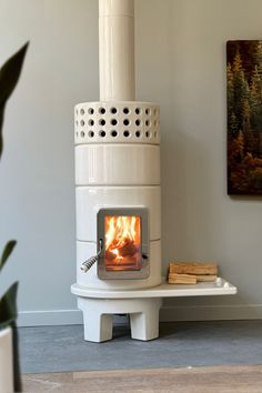 a white stove sitting on top of a wooden floor next to a potted plant