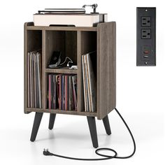 an old record player is plugged in to the side of a wooden cabinet with records on it