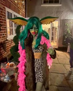 a woman with green hair and pink feathers on her head is dressed in a costume