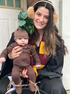 a woman is holding a baby dressed in a costume that looks like a monkey with leaves on its head