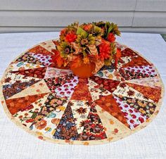 a vase filled with orange flowers sitting on top of a white table cloth covered table