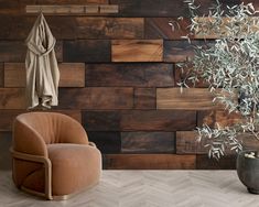 a brown chair sitting in front of a wooden wall next to a potted plant