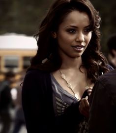 a beautiful young woman standing in front of a yellow school bus and talking on her cell phone