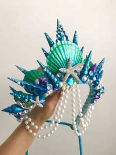 a hand holding a starfish and pearl beaded headpiece