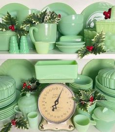 green dishes and cups are arranged on shelves with a clock in the middle, holly wreaths around them