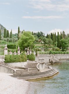 an outdoor area with steps leading up to the water's edge and trees in the background