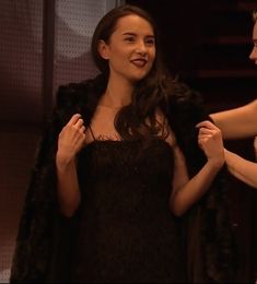 two women standing next to each other in front of a mirror and one is wearing a black dress