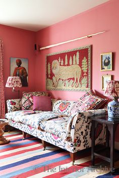 a living room with pink walls and colorful rugs on the floor next to a couch