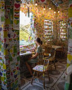 a woman sitting at a table in front of a window covered in hearts and other decorations