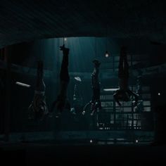 three people are suspended upside down in the dark, while one person is standing up