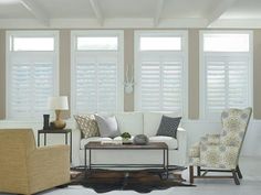 a living room filled with furniture and windows covered in white shuttered glass coverings