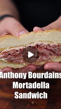 a person holding a sandwich in their hands with the words anthony bourdaiis mortadella sandwich