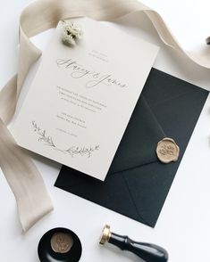 a wedding card and wax stamp on top of an envelope next to a ribbon tied around it