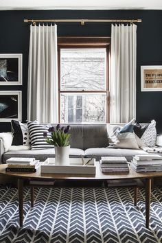 a living room filled with furniture and a window covered in white drapes next to a coffee table