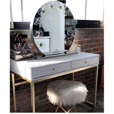 a vanity table with a mirror and stool in front of a brick wall behind it