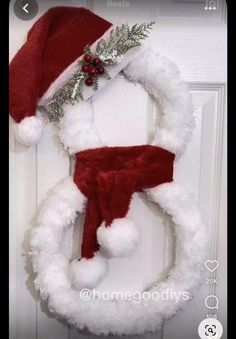 a snowman wreath hanging on a door with a santa hat and scarf attached to it