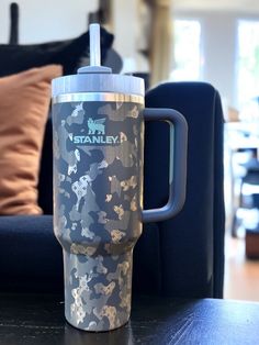 a travel mug sitting on top of a table next to a blue couch in a living room