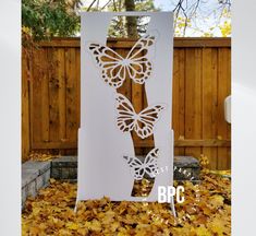 a white paper cut out of butterflies on top of leaves in front of a fence