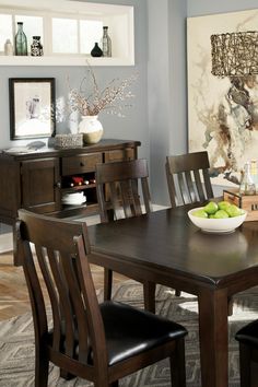 a dining room table with chairs and a bowl of fruit on it