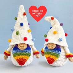 two crocheted gnomes with hats on their heads, one wearing a rainbow colored hat