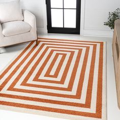 an orange and white area rug in a living room with a couch, chair and window